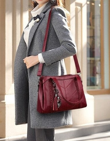 Model draagt schoudertas dames rood met afneembare band, vele vakken en afneembare katten sleutelhanger met rode franjes