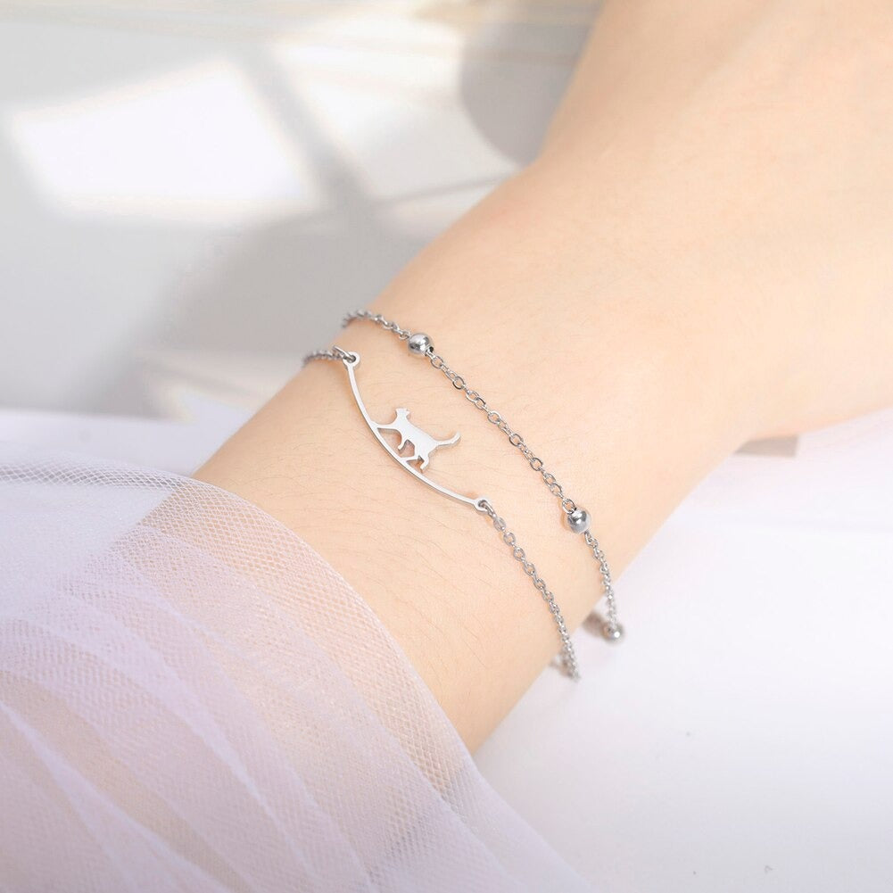 Dubbelle armband zilverkleurig die bestaat uit 2 losse delen. Éen met wandelende kat, ander met balletjes.