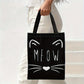 Model draagt zwarte tote bag met witte kattensnoet en MEOW tekst